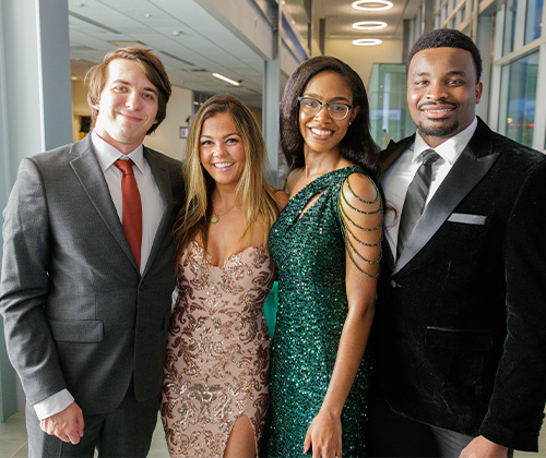 Four students dressed in cocktail attire for a student event
